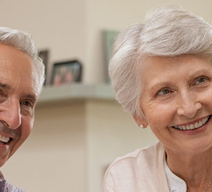 Two seniors smiling and talking to someone