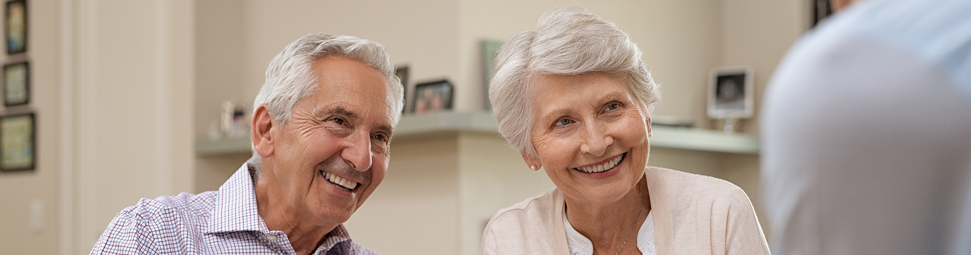 Two seniors smiling and talking to someone