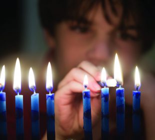 Boy lighting menorah