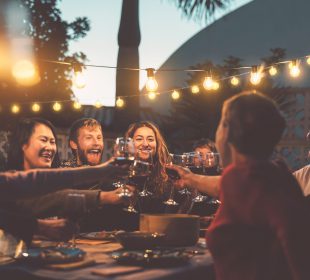 Happy family dining and tasting red wine glasses in barbecue dinner party - People with different ages and ethnicity having fun together - Youth and elderly parents and food weekend activities concept