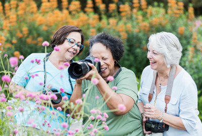 Three senior women taking photos in garden