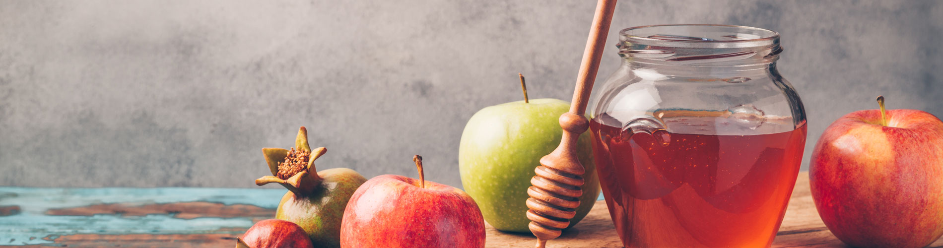 Honey jar and apples on wooden table
