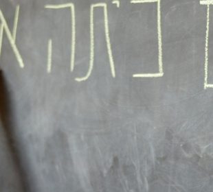 Little girl writes Hello First Grade greetings in Hebrew