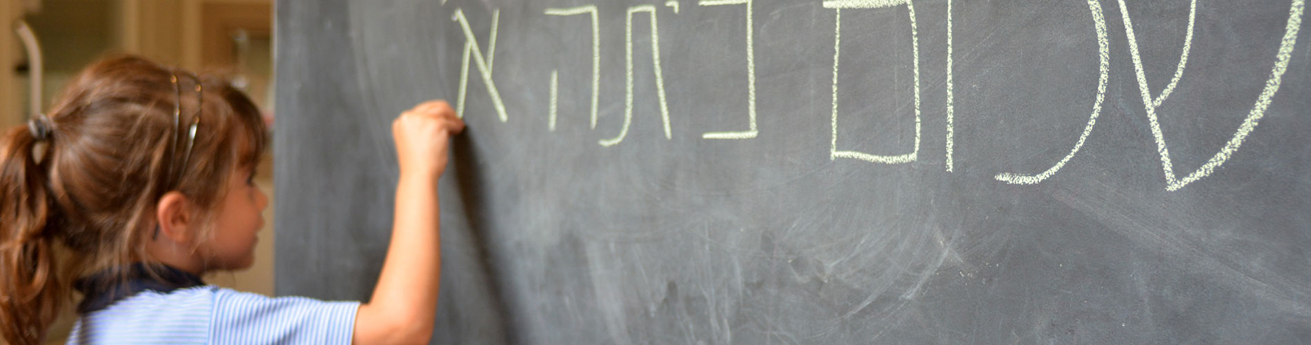Little girl writes Hello First Grade greetings in Hebrew