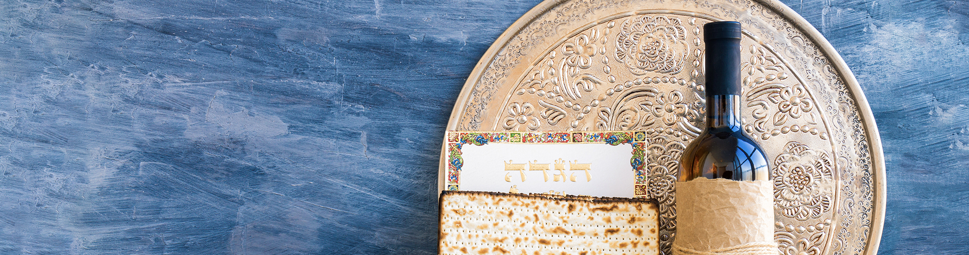 Metal plate with matzah or matza and Passover Haggadah on a vintage wood background presented as a Passover seder feast or meal.