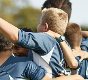 boys sports team cheering and hugging