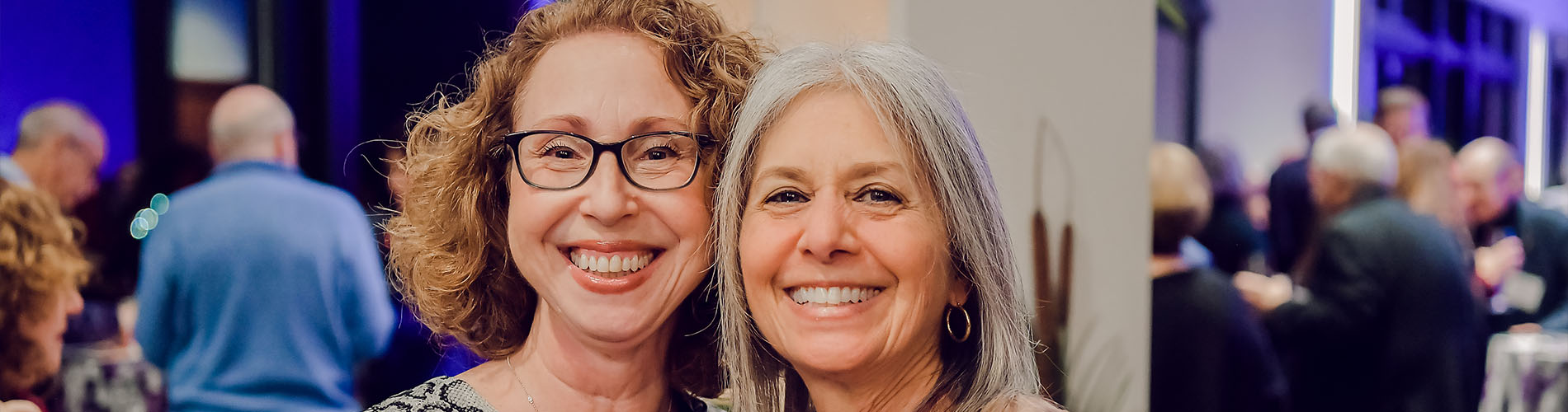Two smiling women attending Associated event