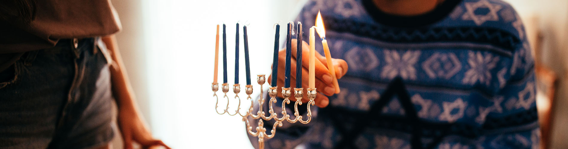 Man lighting candle on dreidel for Chanukah
