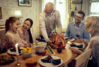 Senior man serving Thanksgiving turkey to the table for family dinner