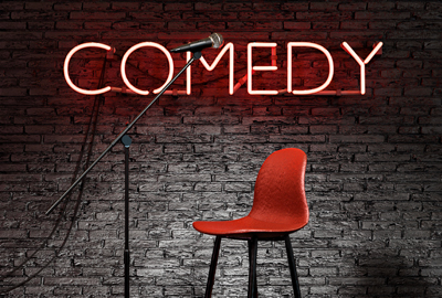 Stage lit by a spotlight and a red neon lamp with the word COMEDY