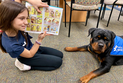 girl reading to Lucy, the Rottweiler