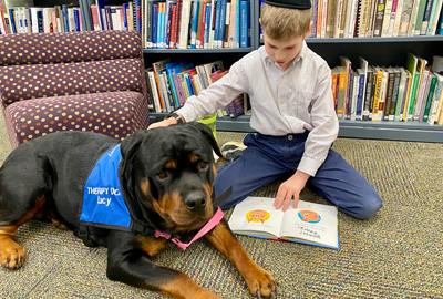 boy reading to Lucy, the Rottweiler