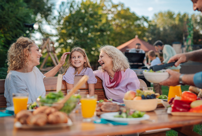 Happy family enjoying backyard barbecue: grandmother, mother, and daughter sharing a laugh