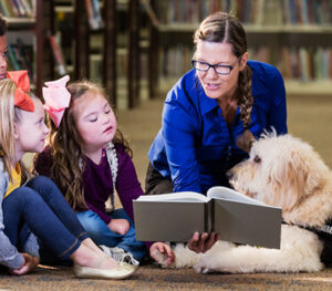 Teacher reading to students and support dog