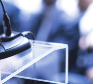 speaker talking at a podium in front of a crowd