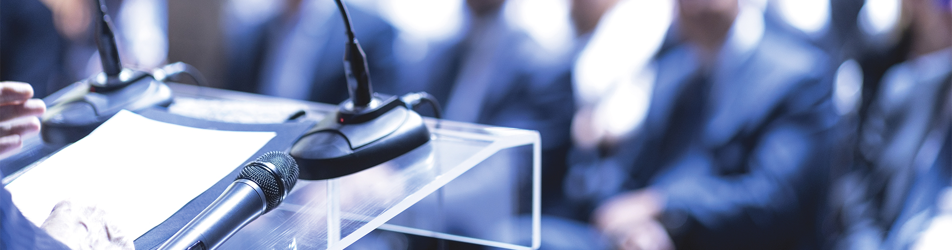 speaker talking at a podium in front of a crowd