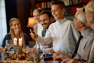 boy lighting the menorah during family meal on Chanukkah