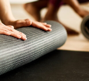 People rolling up yoga mats in class