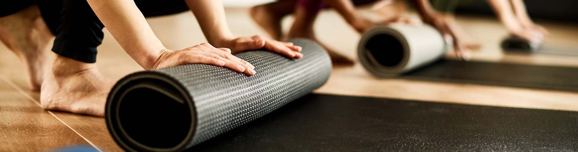 People rolling up yoga mats in class
