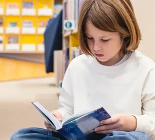 Child at library reading a book