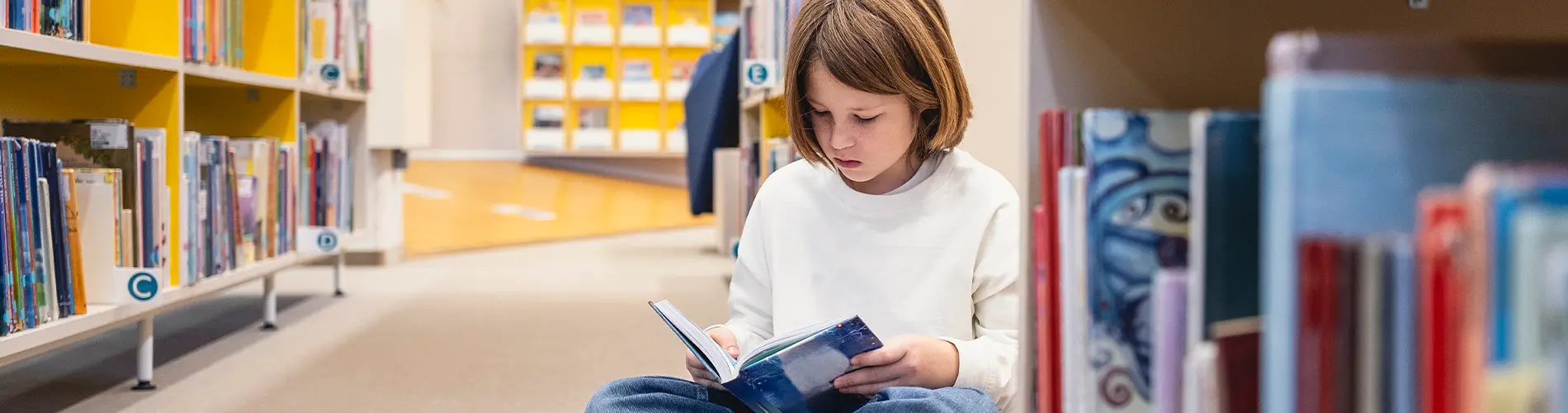 Child at library reading a book