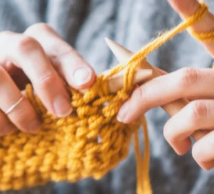woman knitting with yellow yarn